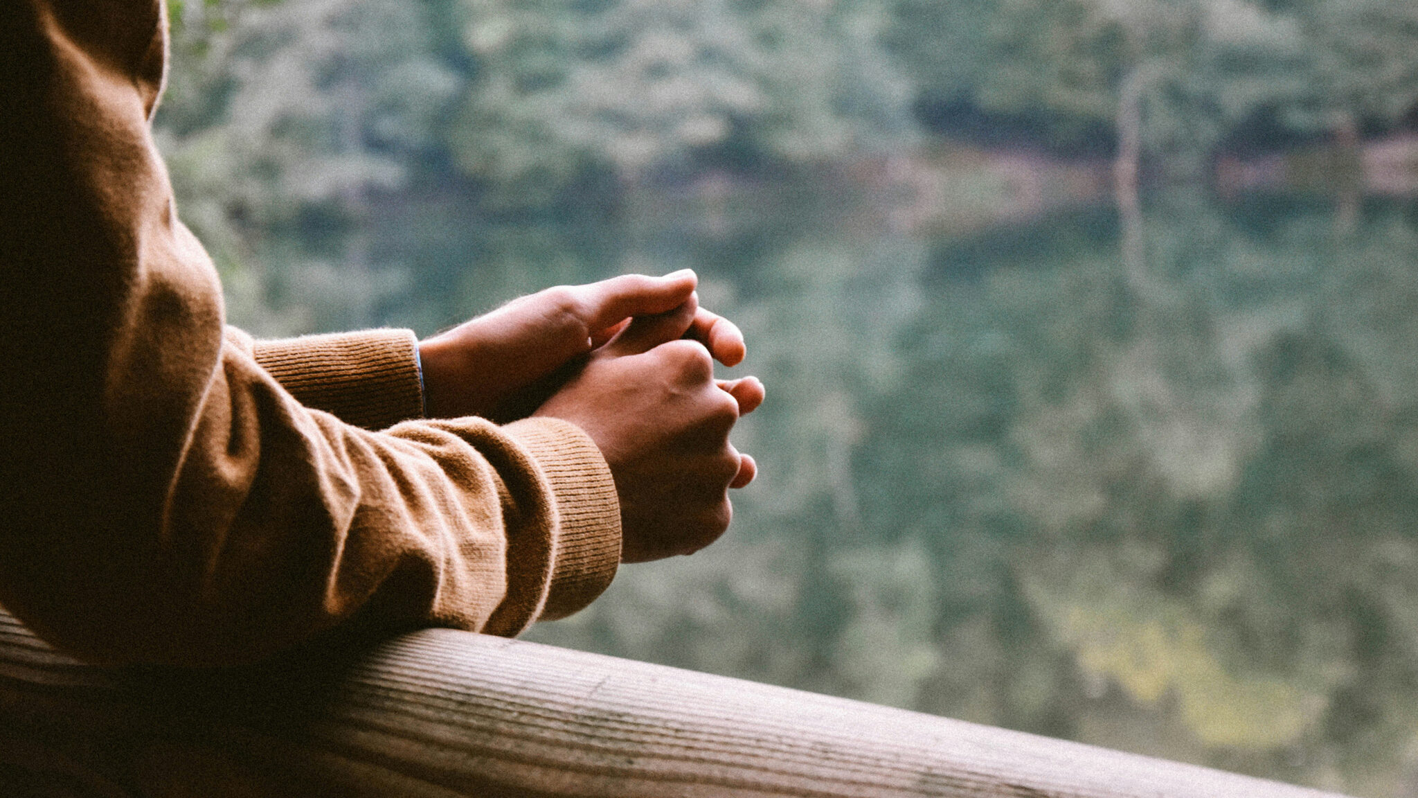 hands clasped over a balcony railing